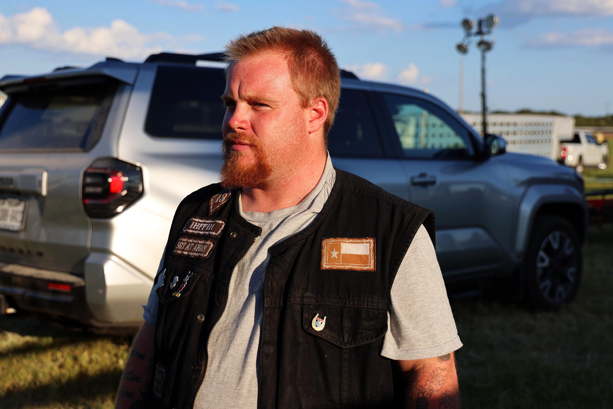 Man with a red beard standing near a truck at the rodeo grounds
