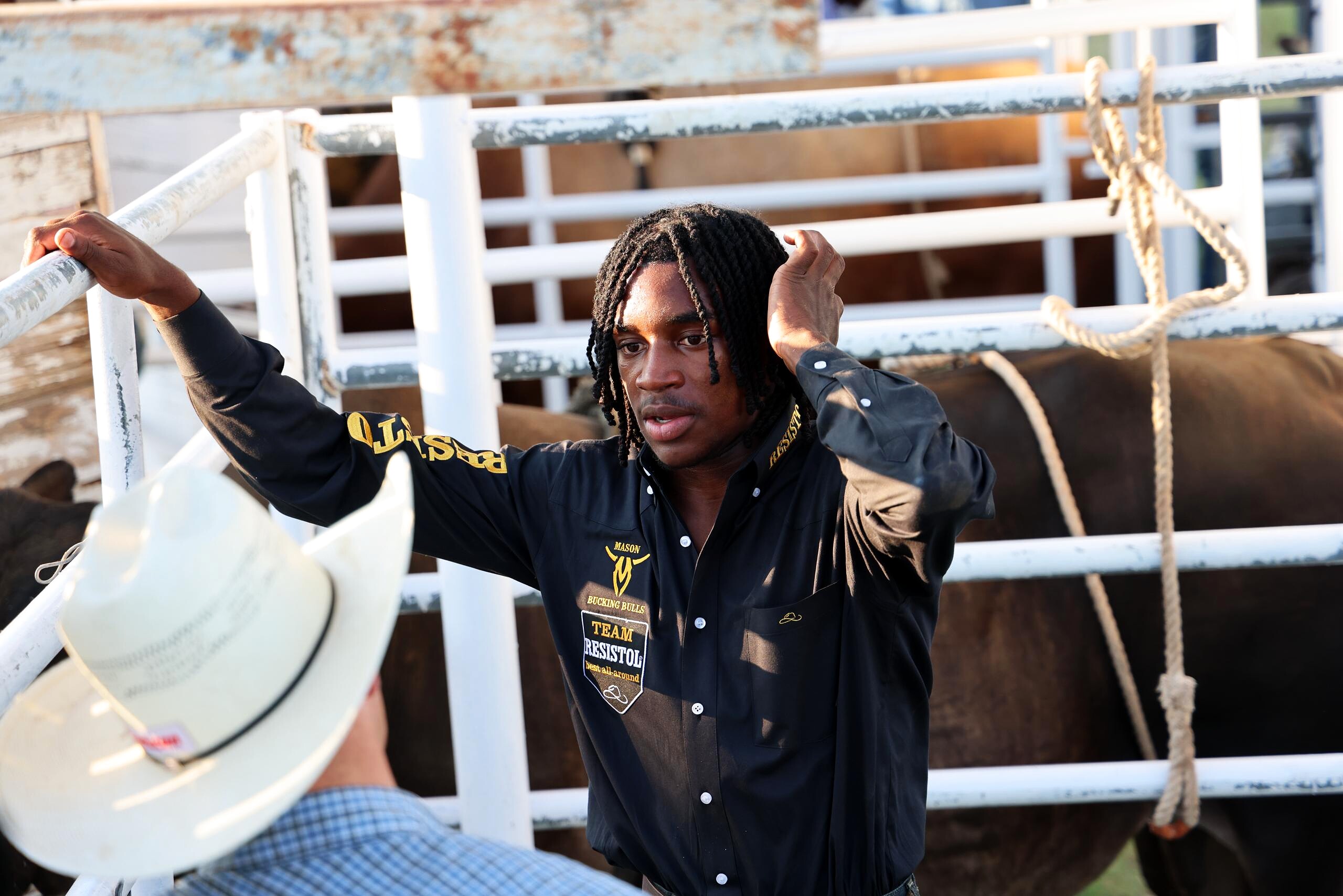 Rider in a black shirt standing beside stock pens